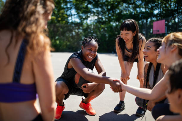 gettyimages-1170568619-612×612 Female basketball player shaking hands during a game plan on court. Multi-ethnic basketball team on outdoor court.